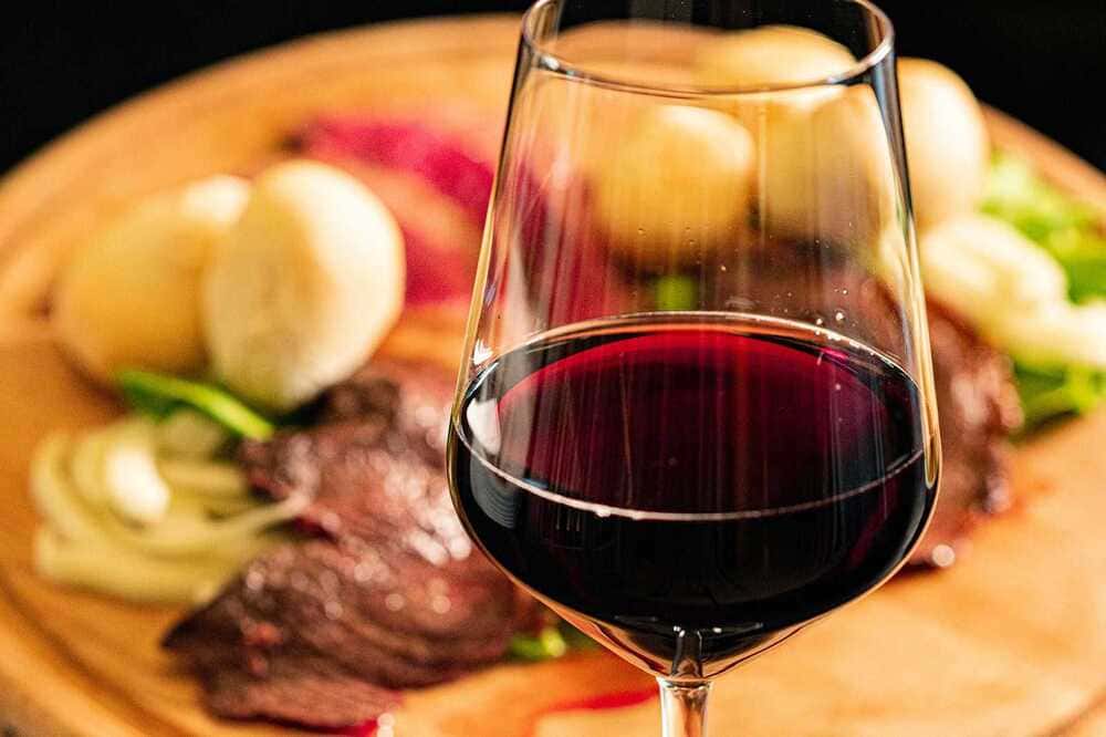 Onde comer em Cabo Frio, descubra nesse post os 10 melhores restaurantes para comer em Cabo Frio. Imagem de um prato saboroso, acompanhado de uma taça de vinho tinto.